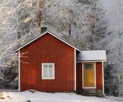 Kuva punaisesta suutarinmökistä talvisena päivänä.